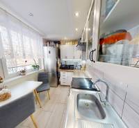 A kitchen in a 2-room apartment with a dining nook, cabinets, and a large window.