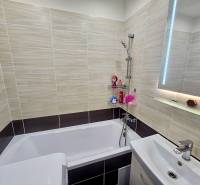 Bathroom in a 2-room apartment with a bathtub, sink, and ceramic tiles.