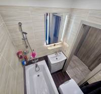 Bathroom in a 2-room apartment with a bathtub and a mirror with lighting.