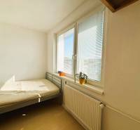 Bright bedroom with a bed, window, blinds, and wood-patterned flooring in a two-room apartment.