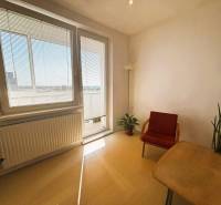 A bright living room with wood-patterned flooring in a two-room apartment, with a red armchair.