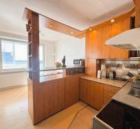 A kitchen in a 2-room apartment with a wood-patterned floor, a spacious window, and a houseplant.