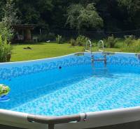 An inflatable pool in the garden of a cottage, surrounded by greenery on Hviezdoslavova Street in Tisovec.