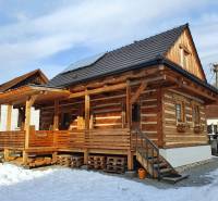 A wooden cottage on Hviezdoslavova Street in Tisovec covered with snow and solar panels.
