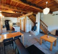 The interior of a cabin with a wooden decor floor, wooden ceiling, and a tiled stove.