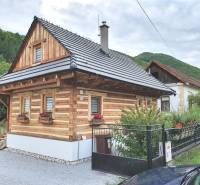 Wooden cottage on Hviezdoslavova Street in Tisovec surrounded by green hills.