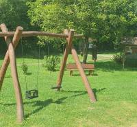 Wooden swings in the park on Hviezdoslavova Street in Tisovec surrounded by greenery.