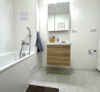 Bathroom in a 3-room apartment with a bathtub, mirror cabinet, and white tiles.