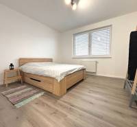 A bedroom in a 3-room apartment with a wood-patterned floor and simple furniture.