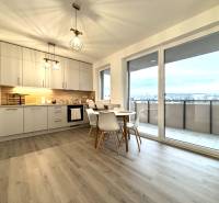 Kitchen in a 3-room apartment with a dining table, wood-patterned floor, balcony doors.