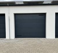 A garage with gray doors on a paved area on Vladimíra Predmerského Street in Trenčín.