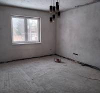 Unfinished room with a concrete floor, large window, and hanging lights in a family house.