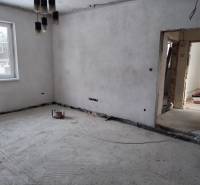 Interior of a family house under construction with bare walls and concrete floor.