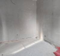 An empty interior with unfinished walls and a concrete floor in a family house.