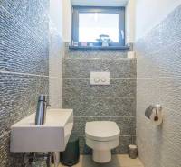 A bathroom in a family house with a sink, toilet, and cozy tiling.