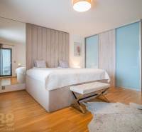 Bedroom in a family house with a bed, wooden decor flooring, and a faux fur rug.
