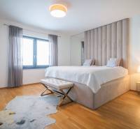 Bedroom in a family house with a bed, wooden decor flooring, and a fur rug.