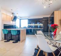 A bright kitchen with a dining table and bar stools in a family house.