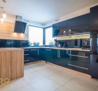 A kitchen in a family house with tiles, black glossy cabinets, and wood decor.
