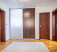 Interior of a family house with a wooden decor floor, a white carpet, and wooden doors.