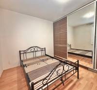 Bedroom in a 3-room apartment with a metal bed and a wardrobe, floor with wooden decor.