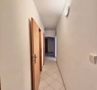 A hallway in a 3-room apartment with tiles, light, and wooden doors to the rooms.