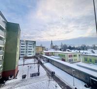 Snow-covered street Centrum in Turzovka with apartment buildings and a distant tower.