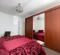 A bedroom with a large wardrobe, chandelier, and bed in a three-room apartment.
