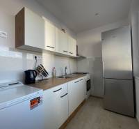 A kitchen in a 3-room apartment with white cabinets and a stainless steel refrigerator.