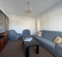 Living room in a 3-room apartment with a comfortable sofa, armchairs, and a display cabinet.