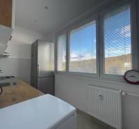 A kitchen in a 3-room apartment with a view through blinds, simple furnishings and appliances.
