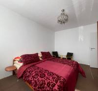 Bedroom with a bed with patterned bedding, ceiling light, and wardrobe in a 3-room apartment.