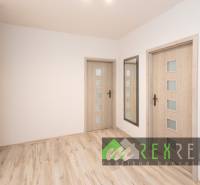 A hallway in a 3-room apartment with a wooden decor floor and a mirror.