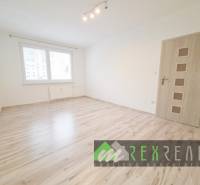 A room in a 3-room apartment with a wood-patterned floor and a window.