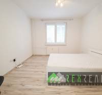 A bright bedroom in a 3-room apartment with a wooden decor floor and simple furniture.