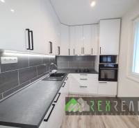 A kitchen in a 3-room apartment with white cabinets and a wooden decor floor.