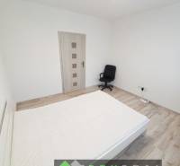 Bright bedroom in a 3-room apartment with wood-patterned flooring and an office chair.