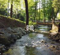 A stream and a bridge surrounded by greenery in Trenčianske Teplice suitable for residential land.