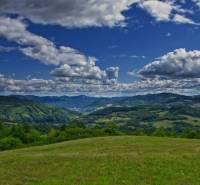 Hills and meadows around Žarnovica under the blue sky, agricultural and forest lands.