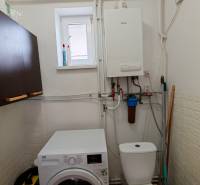 Bathroom in a family house with a washing machine and a boiler, floor with wood decor.