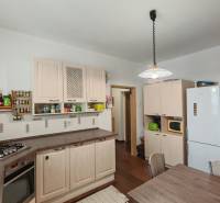 A kitchen in a family house with white cabinets and a wood-patterned floor.