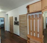 A hallway in a family house with a wooden decor floor, coat racks, and a small bookshelf.