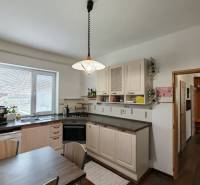A kitchen in a family house with a light, sink, dishwasher, and table, floor with a wooden decor.