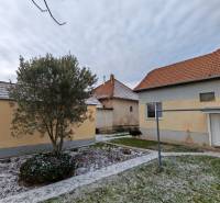 A snow-covered garden with a family house in Trnovec nad Váhom, surrounded by trees and lawn.
