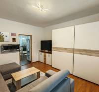 Living room in a family house with a wooden decor floor, a sofa, and paintings on the wall.