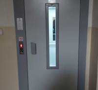 Gray elevator doors in the interior of a one-room apartment with a control panel on the side.