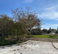 Plots - housing in Malinovo with landscaped area, trees, and blue sky.