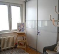 Simple interior of a 3-room apartment with a chair, a small table, and a wardrobe.