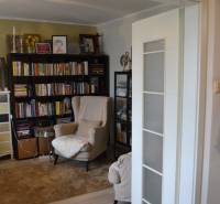 A reading corner with a comfortable armchair and books in a 3-room apartment with a wood-decor floor.