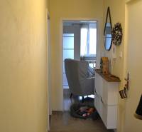 A narrow hallway with wooden floor decor in a 3-room apartment, view into the living room.